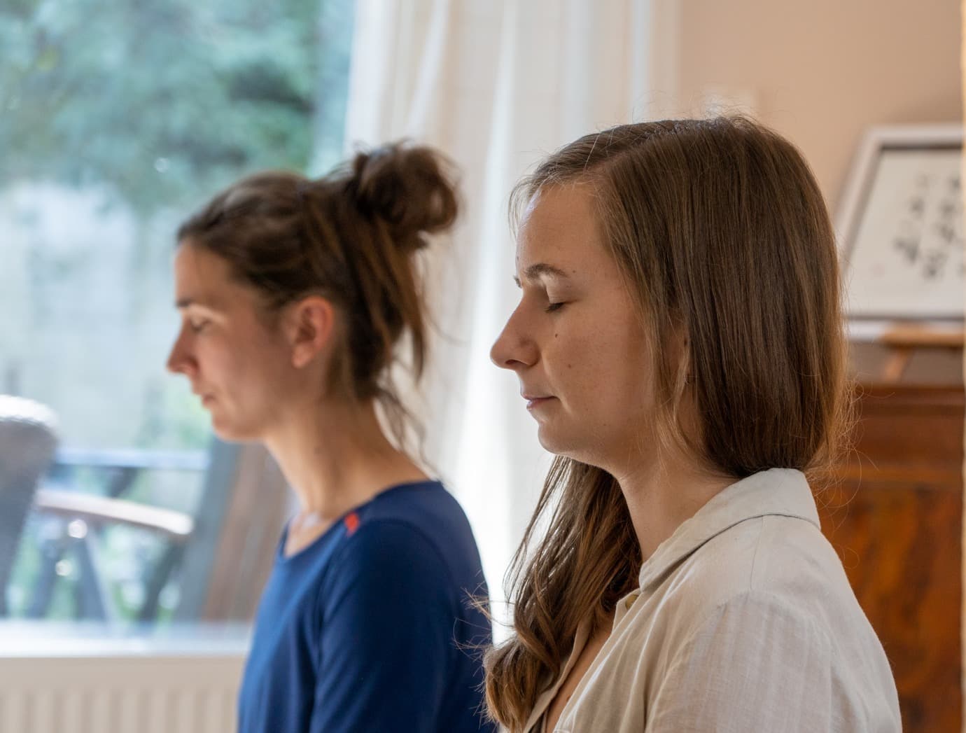 Zwei Teilnehmerinnen sitzen ruhig nebeneinander in Meditation